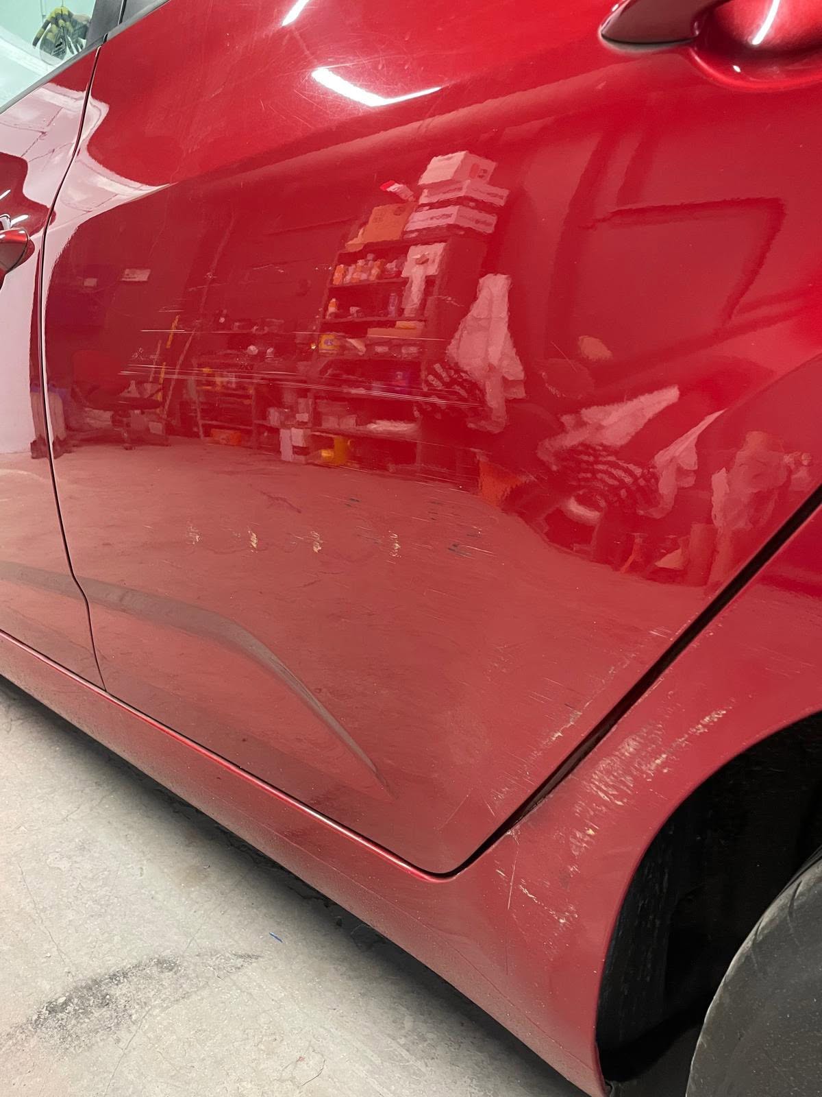Red vehicle door with reflection of the workshop