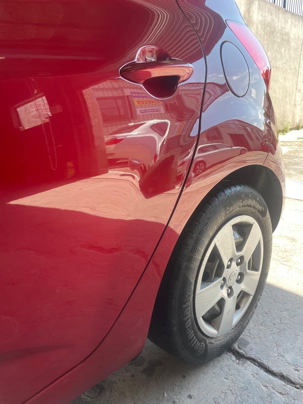 Red car door with chrome handle and white alloy wheel