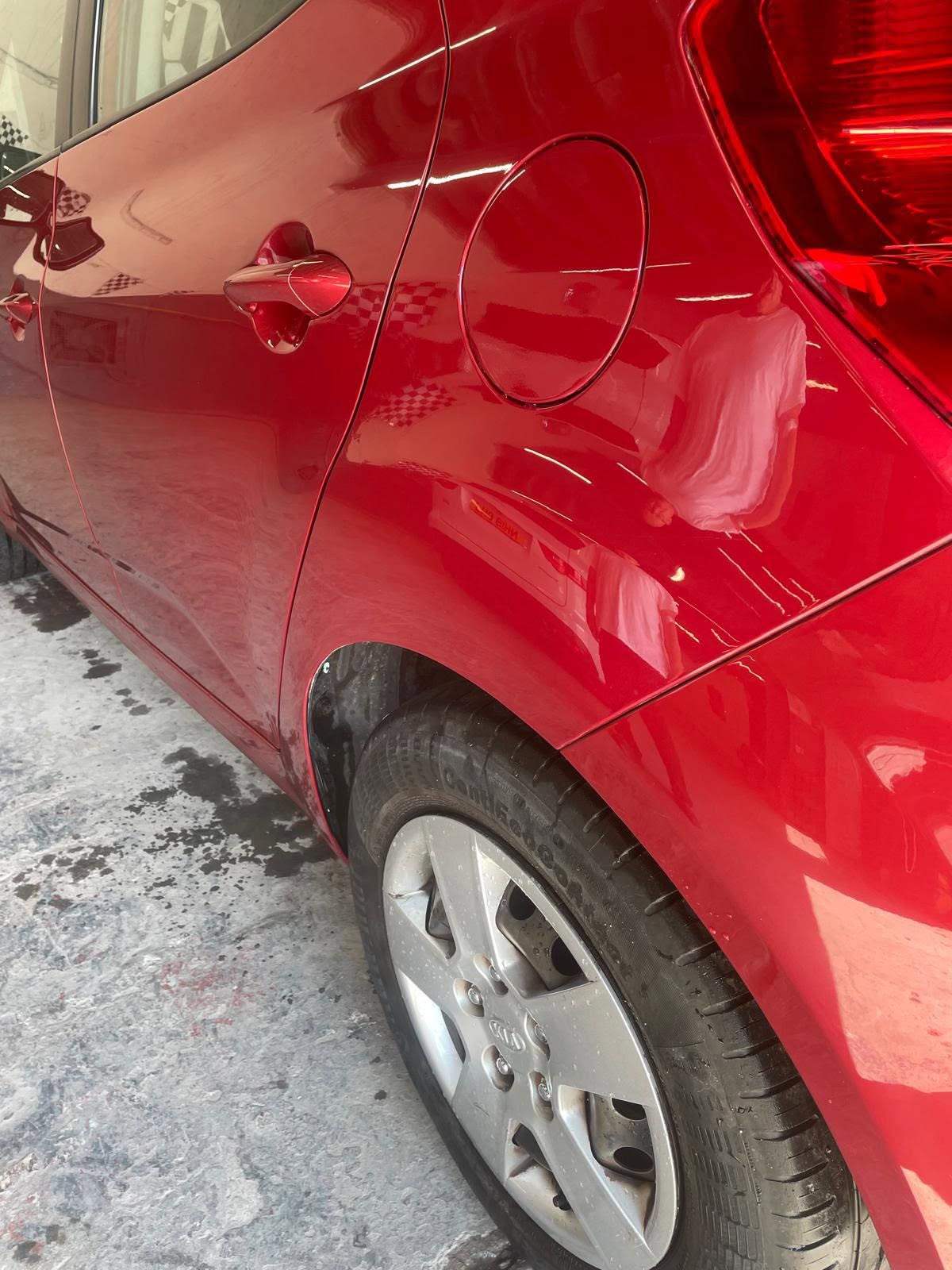 Red car door with dent damage before repair