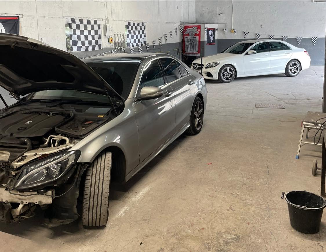 Silver Mercedes saloon with open bonnet in the workshop